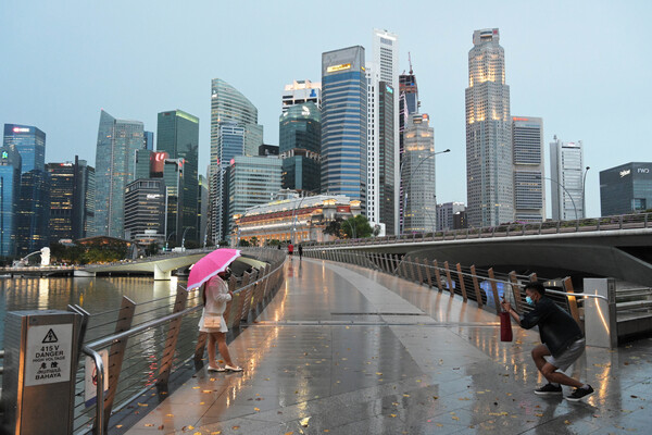 싱가포르가 10년 이내에 아시아에서 인구당 백만장자 비율이 가장 높을 수 있다는 주장이 나왔다. 싱가포르의 비오는 거리에서 시민들이 사진을 찍고 있다. [뉴시스] 